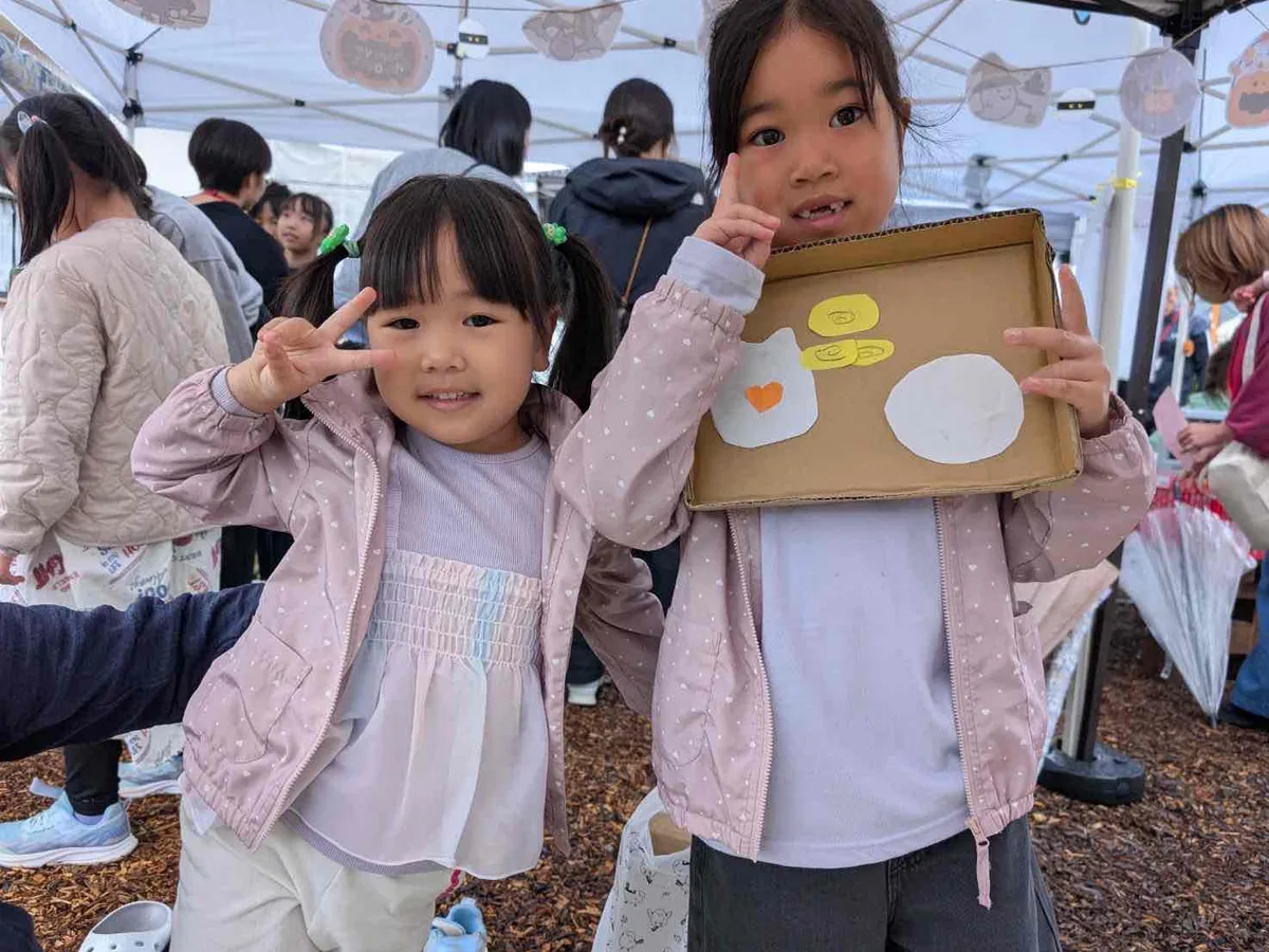 屋外の防災イベントで段ボール製の食器を見せる子どもたち