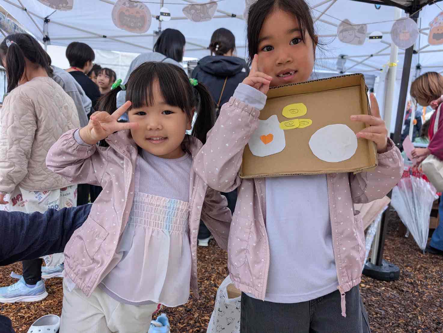 段ボールで作った皿とカップホルダーを手にする子どもたち